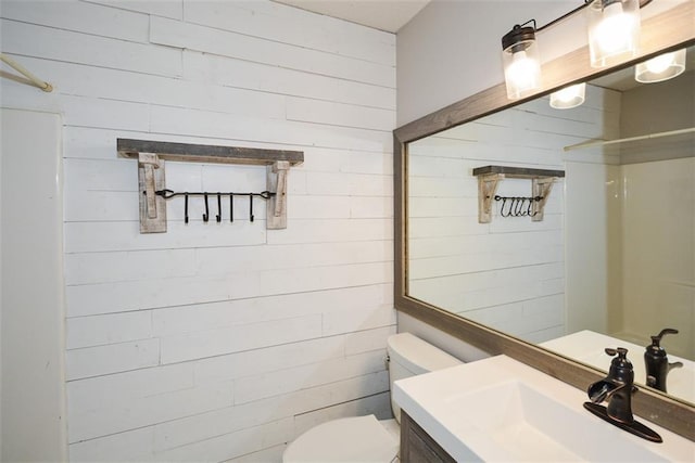 bathroom with wood walls, vanity, and toilet