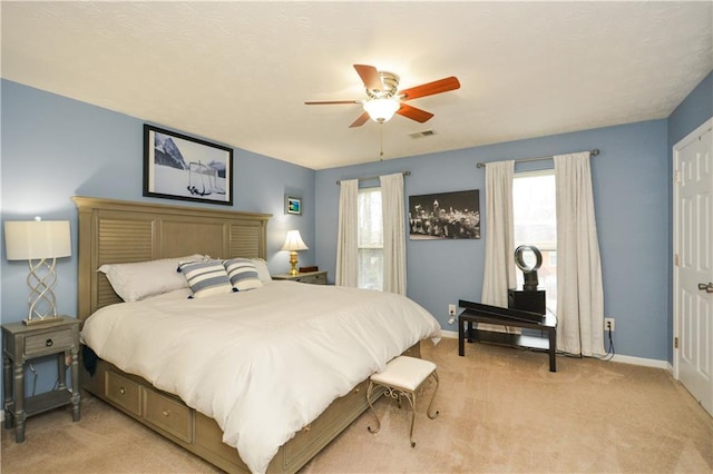 bedroom with multiple windows, light carpet, and ceiling fan