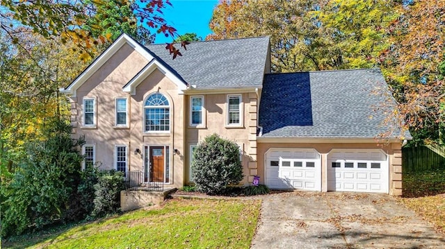 colonial inspired home with stucco siding, roof with shingles, concrete driveway, and an attached garage