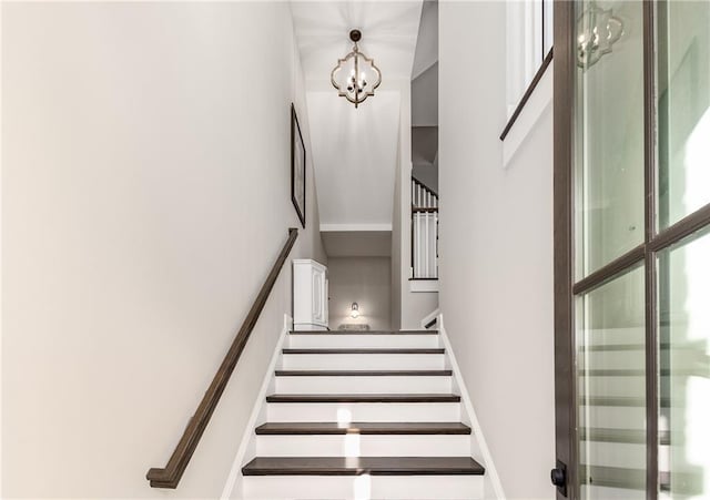 staircase with a notable chandelier