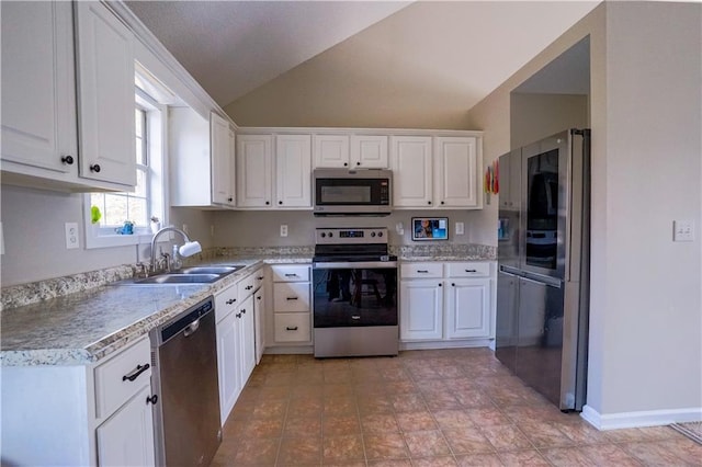 kitchen with a sink, stainless steel appliances, vaulted ceiling, white cabinets, and light countertops