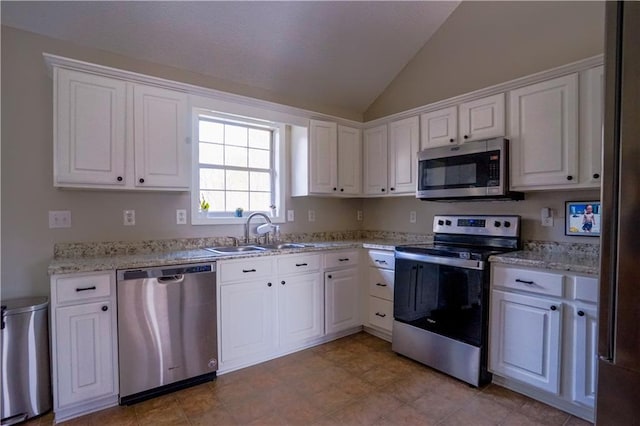 kitchen with white cabinetry, vaulted ceiling, appliances with stainless steel finishes, and a sink