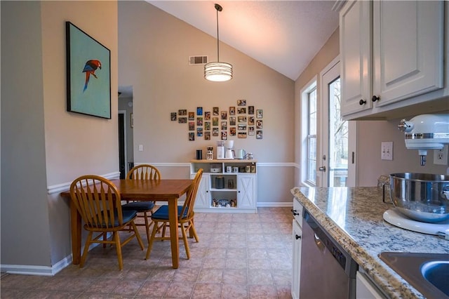 kitchen with baseboards, visible vents, vaulted ceiling, stainless steel dishwasher, and decorative light fixtures