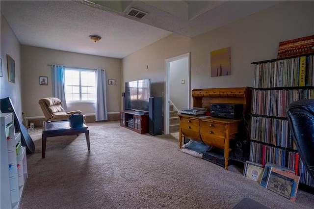 sitting room with stairs, visible vents, carpet floors, and a textured ceiling