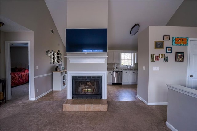 unfurnished living room with lofted ceiling, a sink, a fireplace, dark colored carpet, and baseboards