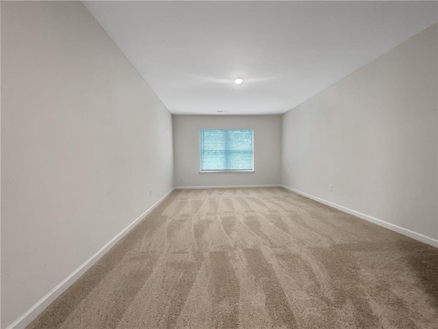 empty room featuring baseboards and light carpet
