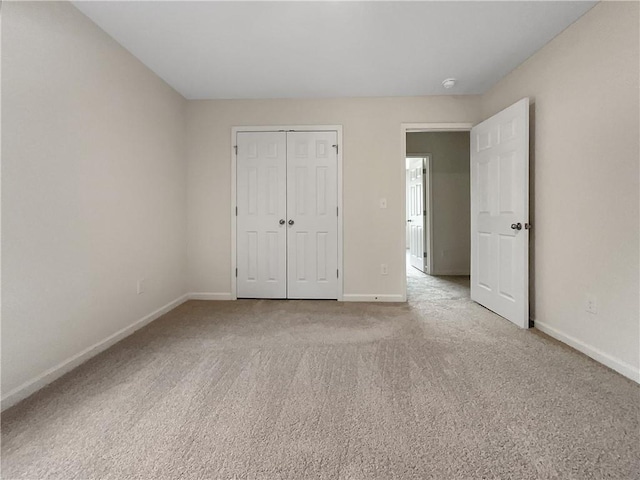 unfurnished bedroom with baseboards, light carpet, and a closet