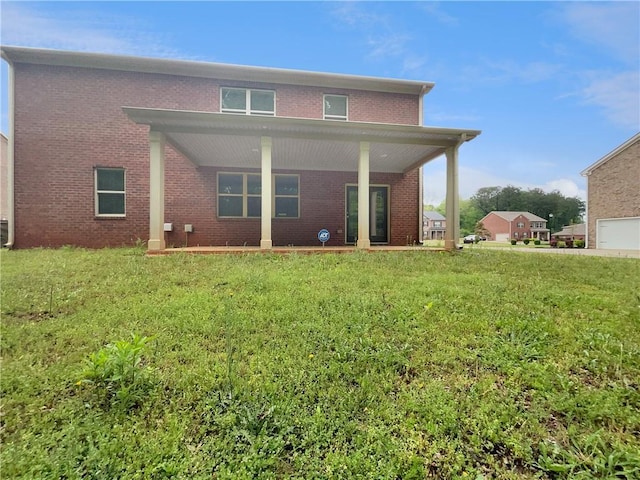 rear view of house featuring a yard and brick siding
