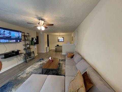 living room featuring wood-type flooring, ceiling fan, and a textured ceiling