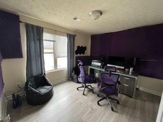 office area with light wood-type flooring, baseboards, and a textured ceiling