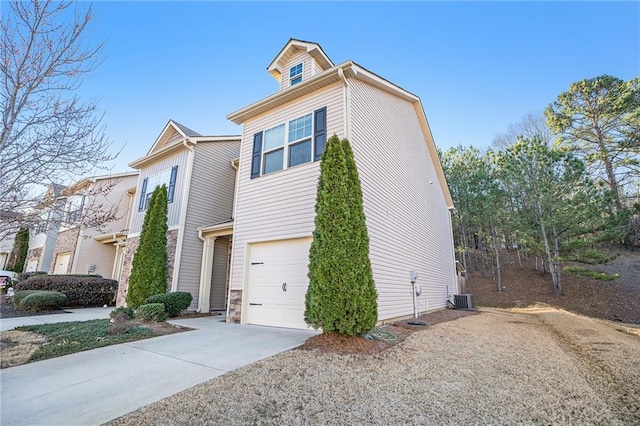 view of front of property featuring a garage, central AC, stone siding, and concrete driveway