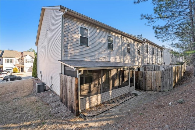 back of property with cooling unit, a sunroom, and fence