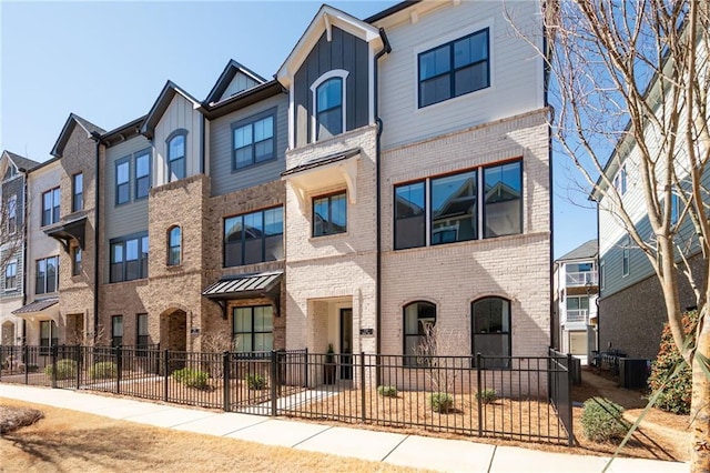 townhome / multi-family property featuring fence, brick siding, board and batten siding, and a residential view