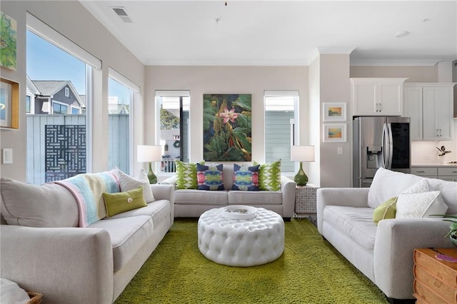 living area featuring visible vents and ornamental molding