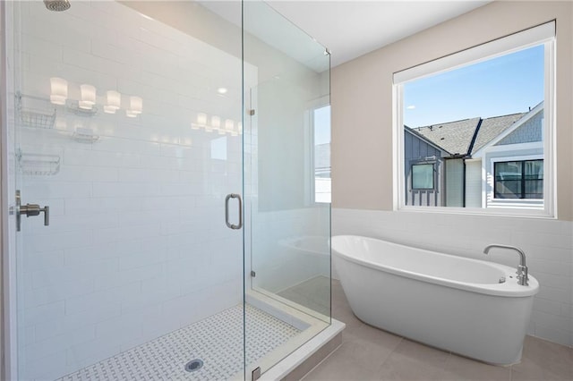 full bathroom featuring a shower stall, a freestanding tub, tile walls, and tile patterned floors