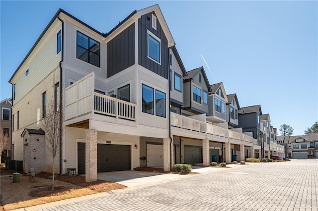 exterior space with a residential view, central AC unit, and an attached garage