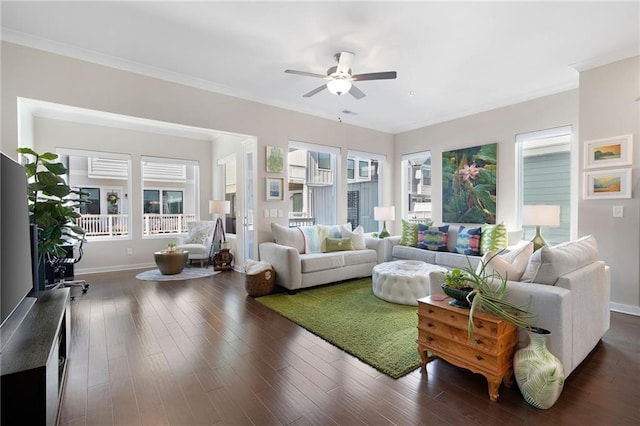 living room featuring dark wood-type flooring, crown molding, baseboards, and ceiling fan