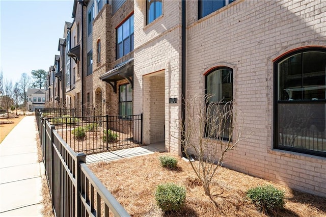 view of side of home with fence, brick siding, and a residential view