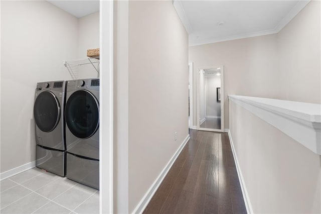 clothes washing area featuring wood finished floors, baseboards, laundry area, washer and dryer, and crown molding