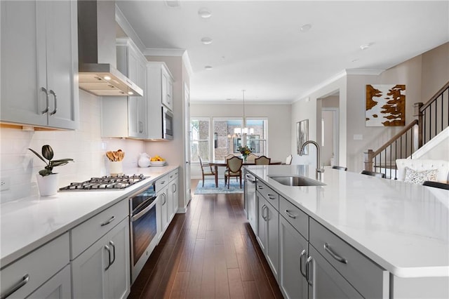 kitchen featuring dark wood-style floors, a sink, light countertops, appliances with stainless steel finishes, and wall chimney exhaust hood