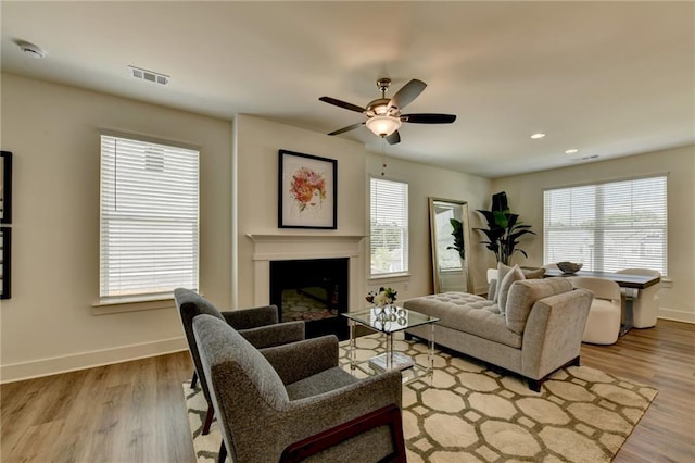 living room with light hardwood / wood-style floors, ceiling fan, and a healthy amount of sunlight