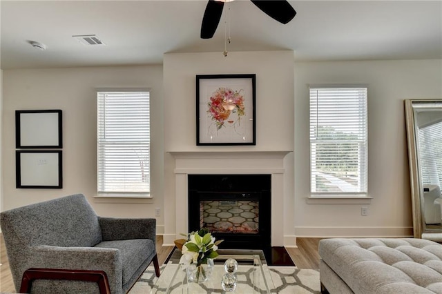 living room with light hardwood / wood-style floors, ceiling fan, and a wealth of natural light