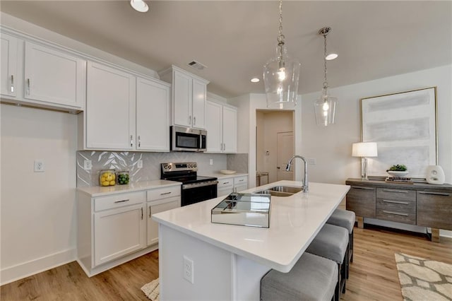 kitchen with white cabinets, an island with sink, and appliances with stainless steel finishes