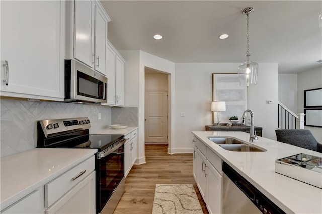 kitchen with stainless steel appliances, hanging light fixtures, decorative backsplash, sink, and white cabinetry