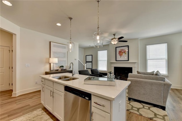 kitchen with sink, white cabinets, dishwasher, light wood-type flooring, and an island with sink