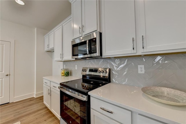 kitchen with stainless steel appliances, white cabinets, decorative backsplash, and light hardwood / wood-style floors