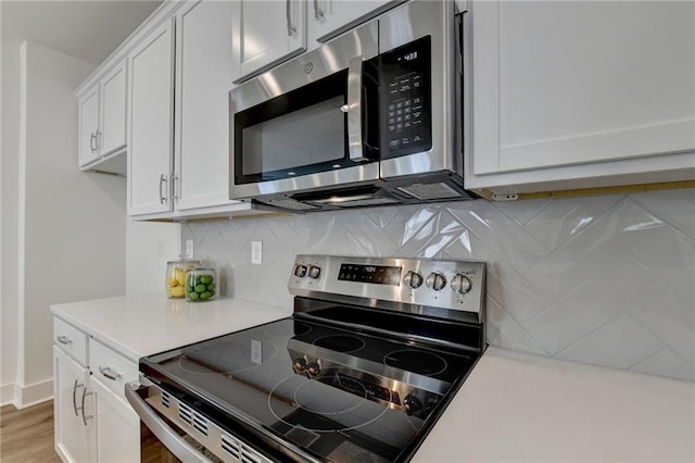 kitchen with light hardwood / wood-style floors, stainless steel appliances, white cabinetry, and backsplash