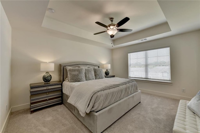 carpeted bedroom featuring a raised ceiling and ceiling fan