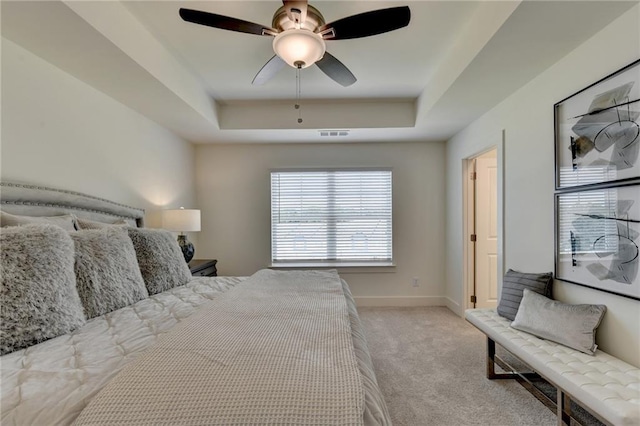 carpeted bedroom featuring a raised ceiling and ceiling fan