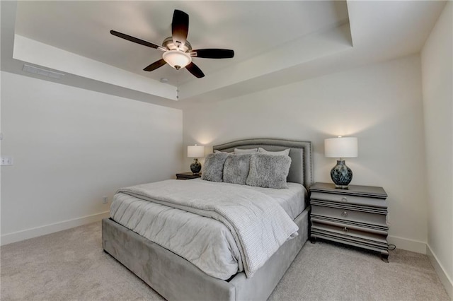 bedroom featuring ceiling fan, a tray ceiling, and light colored carpet