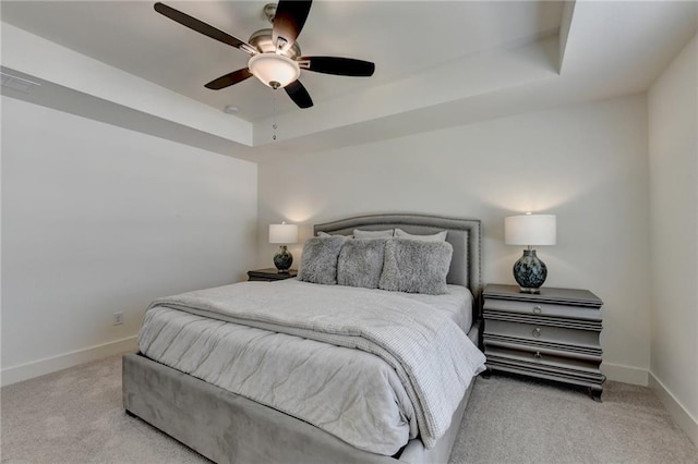 bedroom featuring light carpet, ceiling fan, and a tray ceiling