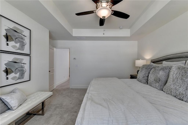 carpeted bedroom featuring ceiling fan and a tray ceiling