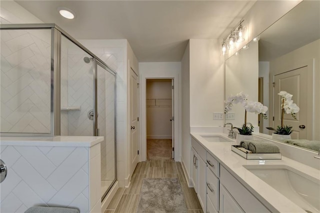 bathroom featuring a shower with shower door and vanity