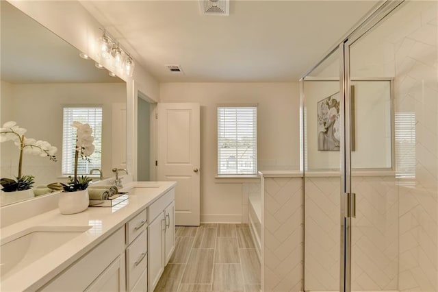 bathroom featuring a wealth of natural light, independent shower and bath, and vanity