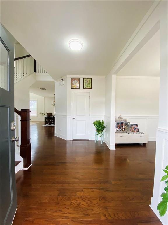 entrance foyer with stairway, a decorative wall, wood finished floors, and wainscoting