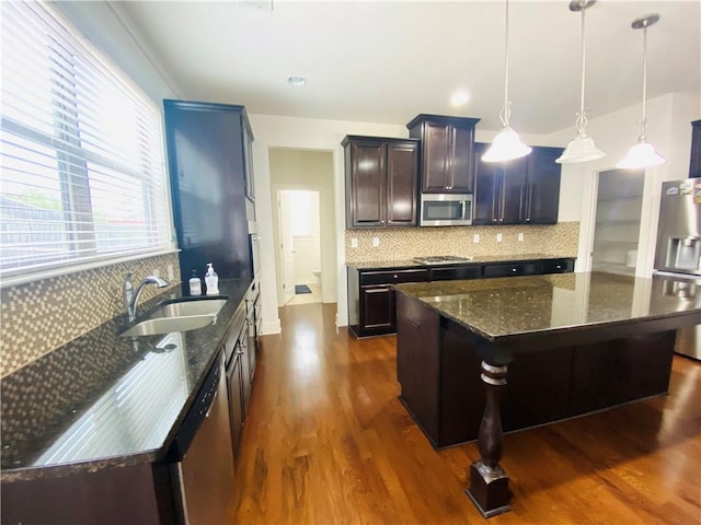 kitchen featuring appliances with stainless steel finishes, dark wood-type flooring, a sink, and tasteful backsplash