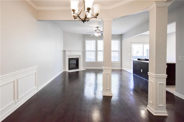 unfurnished living room featuring ceiling fan with notable chandelier, dark hardwood / wood-style floors, decorative columns, and a wealth of natural light