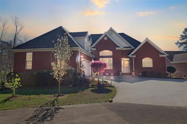 view of front of house with brick siding, a garage, a front lawn, and driveway