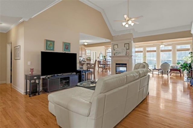 living room with ceiling fan, light wood-type flooring, ornamental molding, and high vaulted ceiling