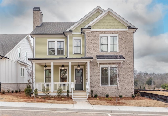 craftsman-style home with brick siding, covered porch, and a chimney