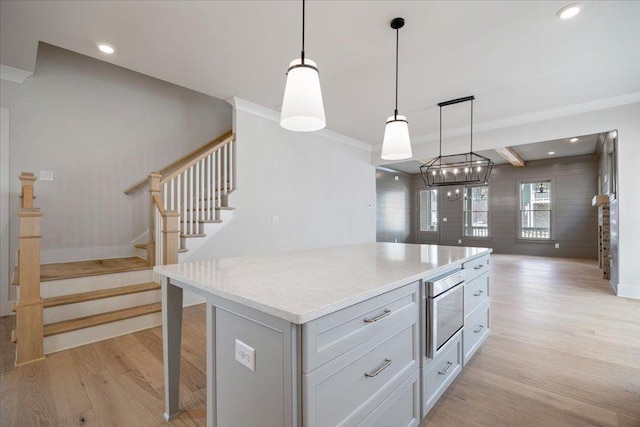 kitchen featuring light countertops, light wood-type flooring, a kitchen island, and pendant lighting