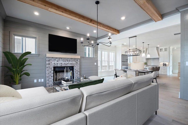 living room with wood walls, beamed ceiling, a tile fireplace, and light wood-style flooring