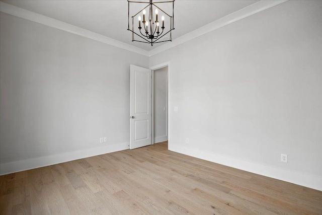 empty room featuring ornamental molding, baseboards, an inviting chandelier, and wood finished floors