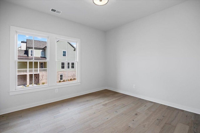 empty room featuring baseboards, visible vents, and wood finished floors