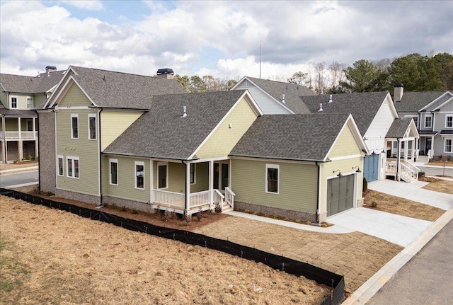 view of front of property with a porch, a shingled roof, concrete driveway, a residential view, and a chimney