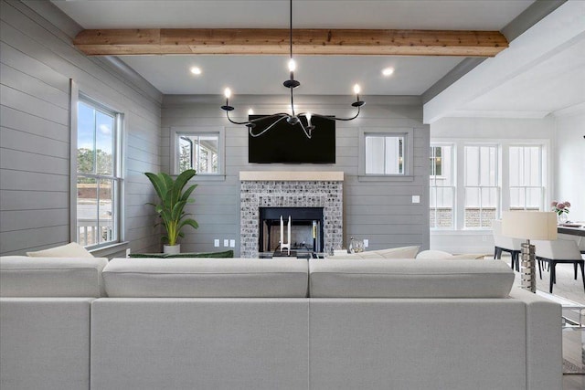 living area featuring beam ceiling, a notable chandelier, and a fireplace